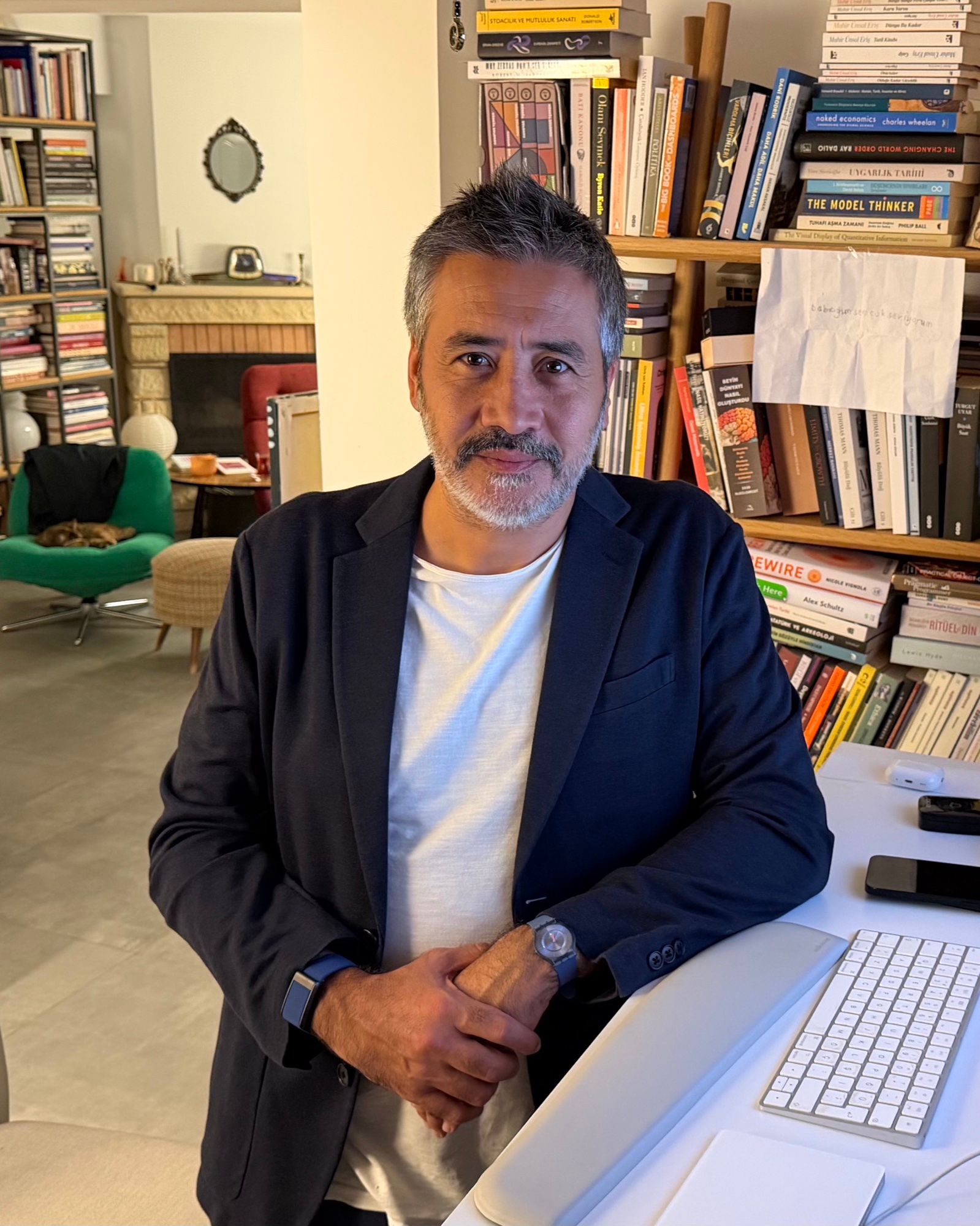 Emre Güneş, kitap duvarının önünde
